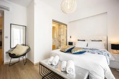 a bedroom with a large white bed and a chair at Luxury 3-bedroom Apartment Athens Nea Smirni in Athens
