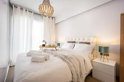 a bedroom with a large white bed with a chandelier at Luxury 3-bedroom Apartment Athens Nea Smirni in Athens