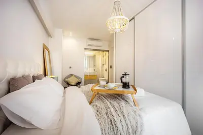 a bedroom with a white bed with a table at Luxury 3-bedroom Apartment Athens Nea Smirni in Athens