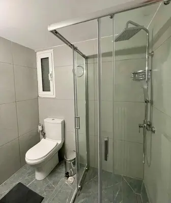 a bathroom with a toilet and a glass shower at Spacious 2-Bedroom Apartment - 10 minutes from Kallimarmaro in Athens