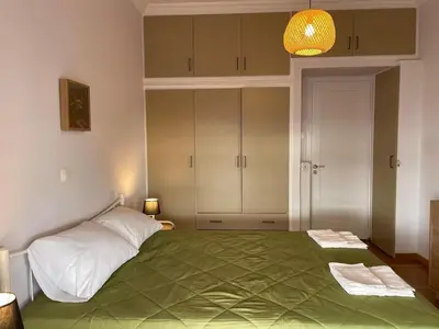 a bedroom with a large bed with a green blanket at Spacious 2-Bedroom Apartment - 10 minutes from Kallimarmaro in Athens