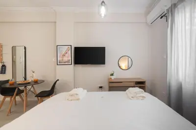 a white bedroom with a bed and a table at Cozy Studio in Plaka 10 Minutes From Acropolis in Athens