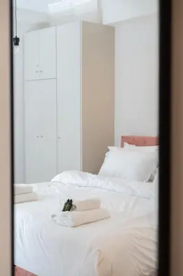 a bed with white sheets and towels on it at 1BR Apt with Backyard in Plaka 10 From Acropolis in Athens