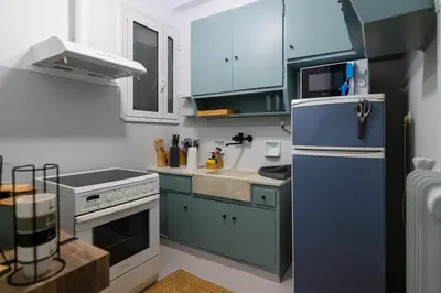 a small kitchen with blue cabinets and a refrigerator at Pangrati Subtle Deluxe Minimalism in Athens