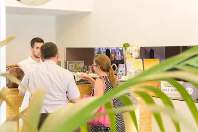 a group of people standing at a counter in a store at Athens Choice Hotel in Athens