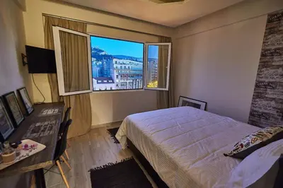 a bedroom with a bed and a desk and two windows at Lycabettus View 2, brand-new, central, cozy studio in Athens