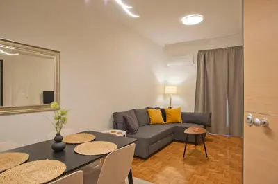 a living room with a couch and a table with chairs at Charming Kallithea Apt, fully Reno, Fully Equipped in Athens