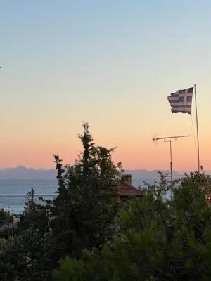 an american flag flying over the ocean at sunset at Sea La Vie, Glyfada in Athens