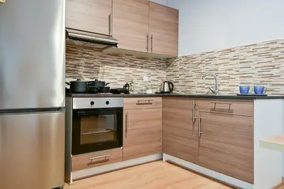 a kitchen with wooden cabinets and a stainless steel refrigerator at 2 Bedroom Apartment near Piraeus Port B1 in Piraeus