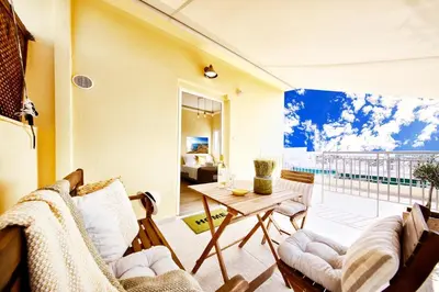 a living room with a table and chairs and a balcony at Island In The Sky, Acropolis and City Views! in Athens
