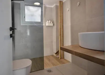 a bathroom with a sink and a toilet and a window at Piraeus Pasalimani LargeTerrace Seaview Apartment in Piraeus