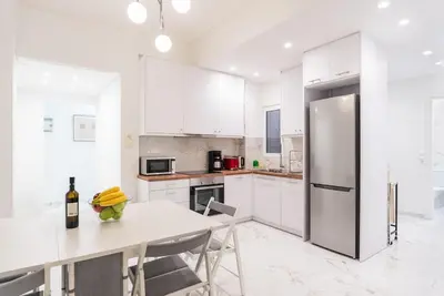 a white kitchen with a table and a refrigerator at Athena's Escape-Your Greek base! in Athens