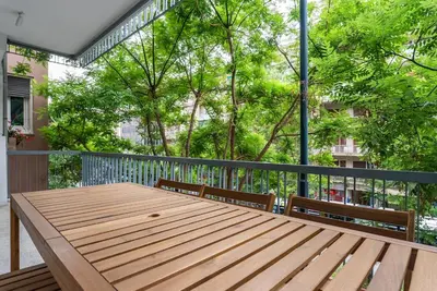 a wooden table and chairs on a balcony with trees at Athena's Escape-Your Greek base! in Athens