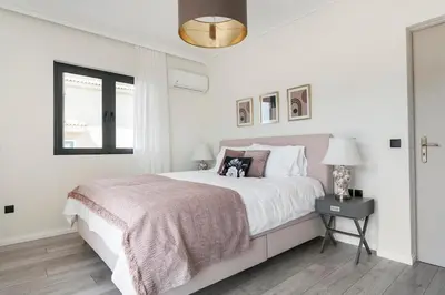 a white bedroom with a large bed and a window at Luxury 3-BD condo with 80sqm balcony in Glifada in Athens
