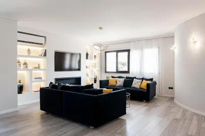 a living room with a black couch and a tv at Luxury 3-BD condo with 80sqm balcony in Glifada in Athens