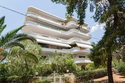 a tall white building with trees in front of it at Luxury 3-BD condo with 80sqm balcony in Glifada in Athens