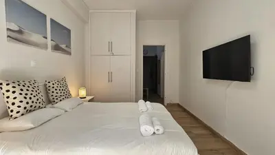 a bedroom with a white bed with a flat screen tv at Lotus Suite Ampelokipoi in Athens