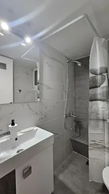 a white bathroom with a sink and a shower at Lotus Suite Ampelokipoi in Athens