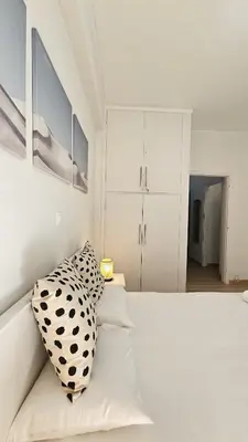a white bed with a black and white pillow on it at Lotus Suite Ampelokipoi in Athens