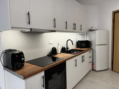 a kitchen with white cabinets and a sink and refrigerator at Calma Athens in Athens