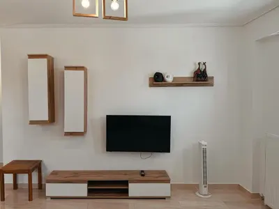a living room with a tv on a white wall at Seaview Complex with Pool in Porto Rafti