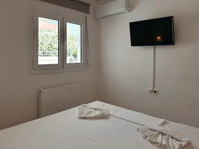 a white room with a bed with a television on the wall at Seaview Complex with Pool in Porto Rafti