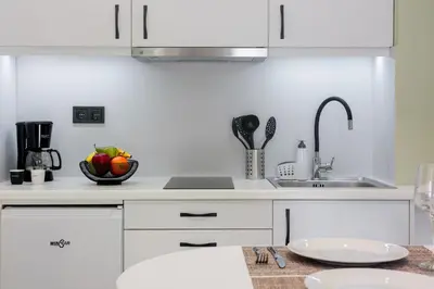 a white kitchen with a sink and a bowl of fruit at Kais eleven studio in Athens