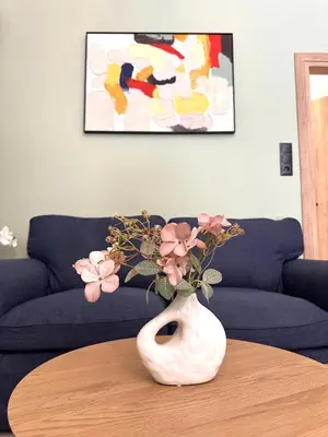 a white vase with pink flowers on a table at Panathenaic Stadium area Model Cozy Studio B in Athens