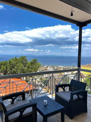 a balcony with two chairs and a table and the ocean at Eleni's Seaview House in Saronida