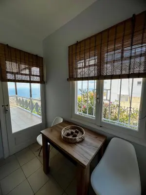 a dining room with a table and two windows at Eleni's Seaview House in Saronida