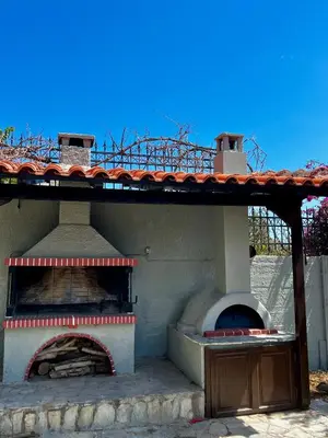 an outdoor pizza oven with a roof on top at Eleni's Seaview House in Saronida