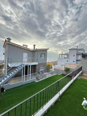 a house with a fence and a green yard at Eleni's Seaview House in Saronida