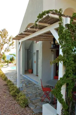 a patio of a house with a table and a chair at Aegean Grace in Áyios Dhimítrios