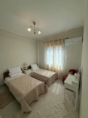 a white bedroom with two beds and a window at A nest for two in Athens in Mesochórion