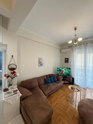 a living room with a brown couch and a tv at A nest for two in Athens in Mesochórion