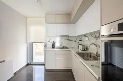 a white kitchen with white cabinets and a sink at City Lights Residence Psyxiko in Athens