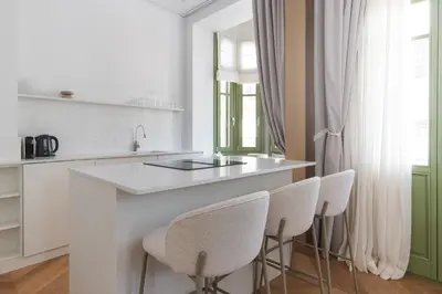 a kitchen with a white counter and white chairs at Ogigou Suites in Athens