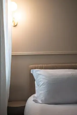 a bed with a white pillow and a lamp at Ogigou Suites in Athens