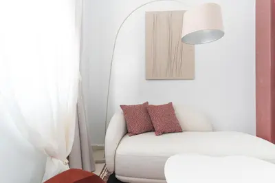 a living room with a white couch and a lamp at Ogigou Suites in Athens