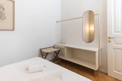 a white bedroom with a bed and a mirror at Ogigou Suites in Athens