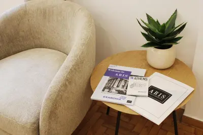 a table with a chair with a book and a plant at ARIS Urban Exarchia in Athens