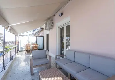 a room with a couch and a chair on a balcony at Athenian Sky, Two Bedroom Apartment in Koukaki in Athens