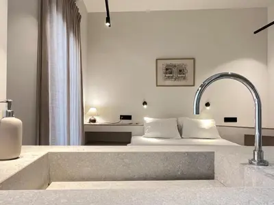 a bathroom with a bed in the background with a sink at Chic Central Gem Walk to Acropolis in 10 minutes in Athens