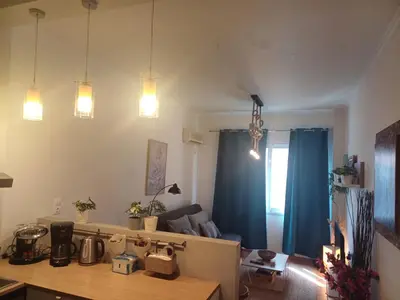 a kitchen and a living room with blue curtains at Argy's cozy apartment in Pireaus Port in Piraeus