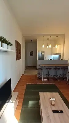 an empty living room with a table and a kitchen at Argy's cozy apartment in Pireaus Port in Piraeus