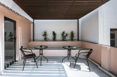 two tables and chairs on a balcony with plants at Kais 1st floor studio in Athens