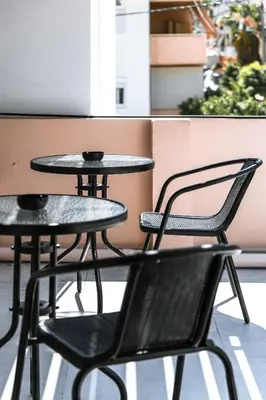 two tables and chairs sitting on a balcony at Kais 1st floor studio in Athens