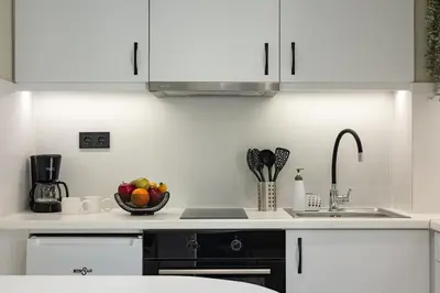 a kitchen with white cabinets and a bowl of fruit at Kais 1st floor studio in Athens