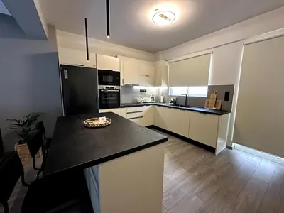a kitchen with white cabinets and a black counter top at Her Luxury Apartment in Athens