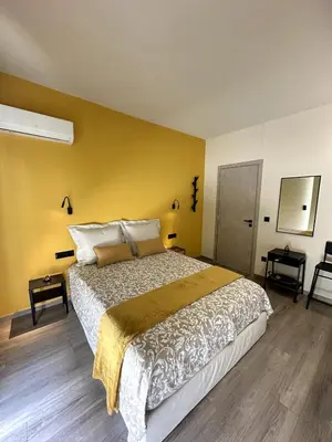 a bedroom with a large bed and a yellow wall at Her Luxury Apartment in Athens